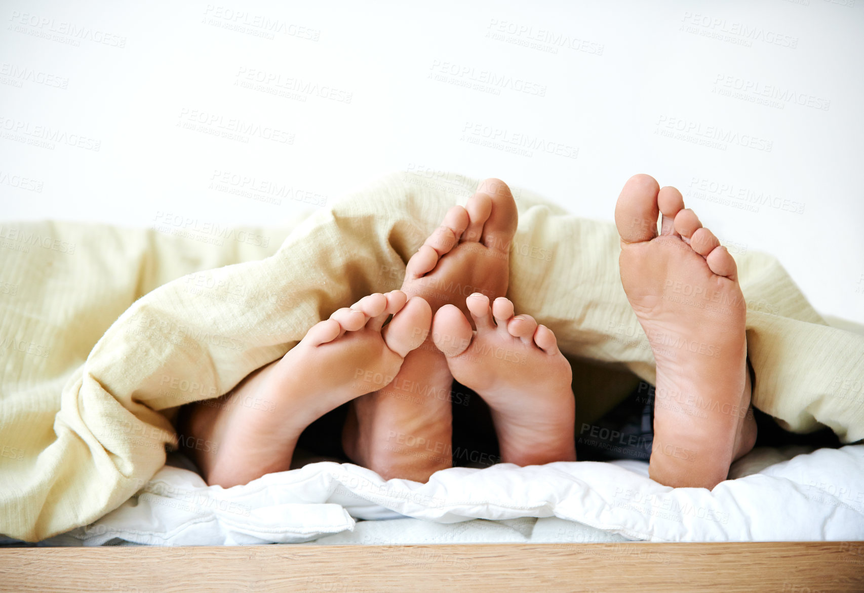 Buy stock photo Cropped shot of a couple's feet poking out from under the bedsheets. Love and tenderness .Loving married couple sleeping in bed together, man caressing woman's legs, closeup of feet under a blanket