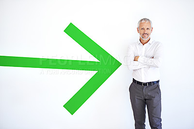 Buy stock photo A mature businessman standing against a white background with a large green arrow pointing at him