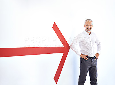 Buy stock photo A mature businessman standing against a white background with a large red arrow pointing at him