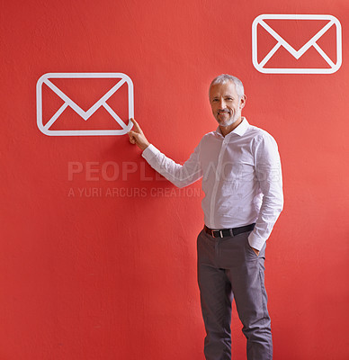 Buy stock photo A mature businessman pointing at a message symbol while standing against a red background