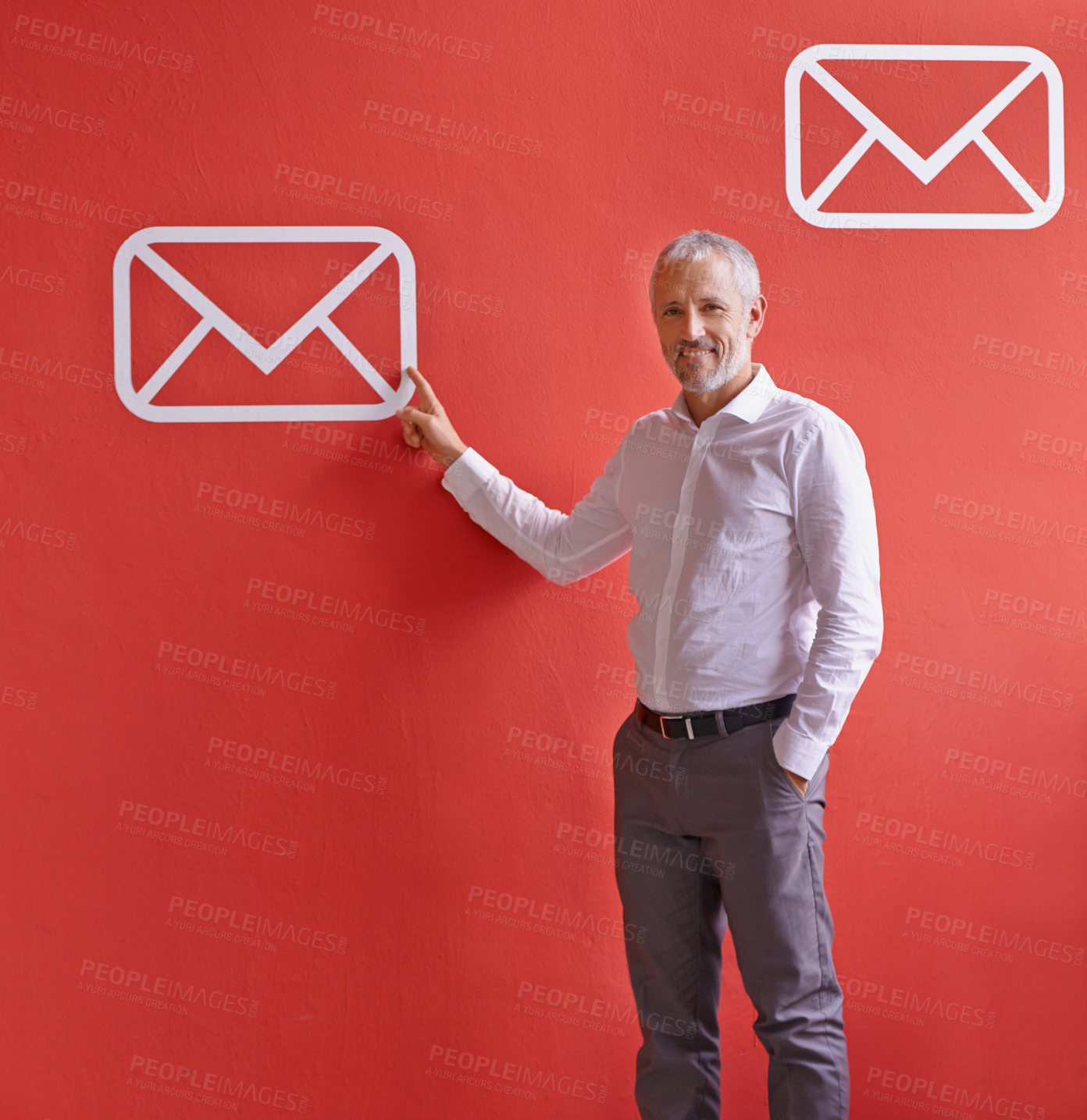 Buy stock photo A mature businessman pointing at a message symbol while standing against a red background