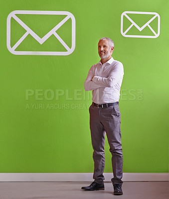 Buy stock photo Shot of a mature businessman standing in front of a green wall with message symbols on it