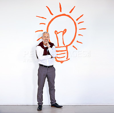 Buy stock photo Portrait of mature businessman standing in front of a white wall with a lightbulb on it