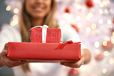 Buy stock photo Shot of a young woman holding presents while sitting by a Christmas tree