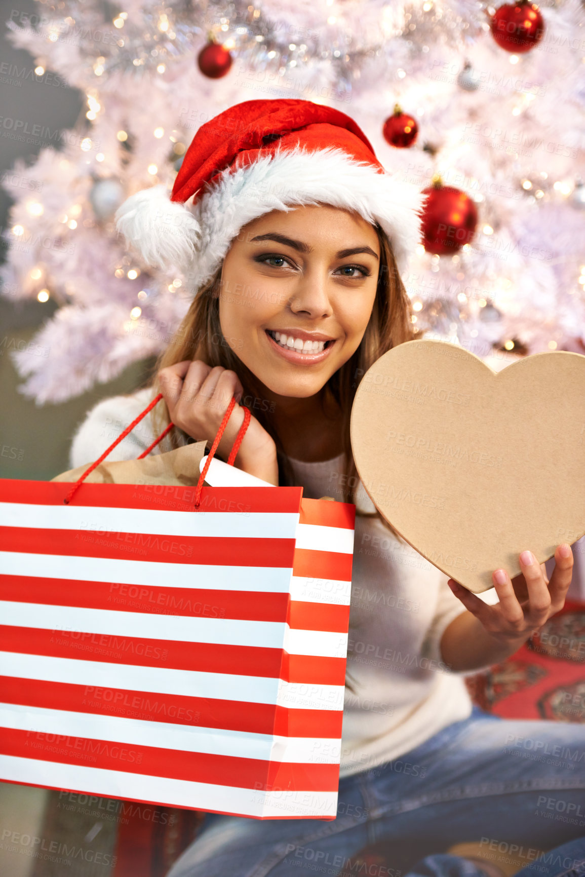Buy stock photo Happy, Christmas present and portrait of woman in home for festive celebration with bag and heart box. Smile, hat and female person with xmas gift at house with holiday decorations in Brazil.
