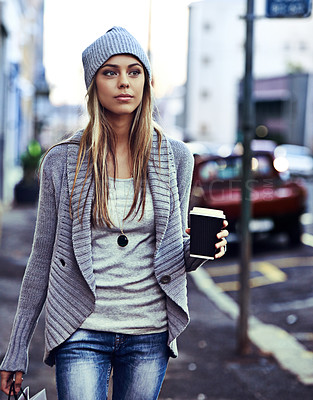 Buy stock photo Shot of a beautiful young woman walking with a shopping bag and takeaway coffee in the city