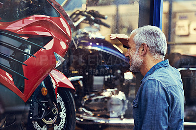 Buy stock photo Shot of a mature man admiring the window display of a motorcycle shop