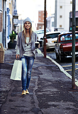 Buy stock photo Portrait of a beautiful young woman walking with a shopping bag and takeaway coffee in the city