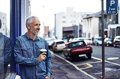 Buy stock photo Shot of a handsome mature man drinking takeaway coffee while out in the city