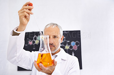 Buy stock photo Shot of a mature male scientist conducting an experiment in his lab