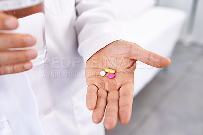 Buy stock photo Cropped shot of a male doctor holding a glass of water and medicine in his hand