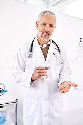 Buy stock photo Portrait of a mature male doctor holding a glass of water and medicine in his hand
