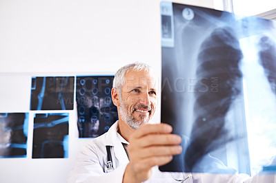 Buy stock photo Shot of a mature male doctor smiling while looking at a x-ray image at a hospital