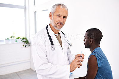 Buy stock photo Portrait of a mature male doctor standing with a syringe with his patient in the background