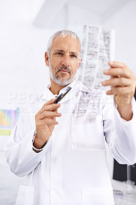 Buy stock photo Shot of a male scientist examining the results of a DNA test