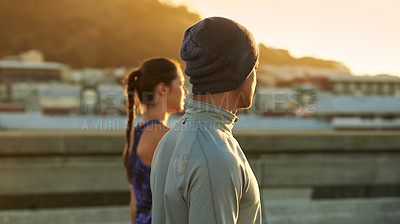 Buy stock photo Shot of two young joggers standing and watching the sunrise