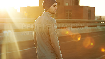 Buy stock photo Shot of a young jogger taking a break on the road in the early morning