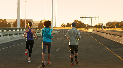 Buy stock photo Urban, street and people running at sunset together for fitness, training or commitment to body health. Evening, exercise and group of friends on road in city workout with outdoor challenge from back