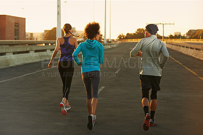 Buy stock photo Fitness, street and people running at sunset together for training, commitment and health in city. Evening, exercise and group of friends on road for urban workout with outdoor challenge from back