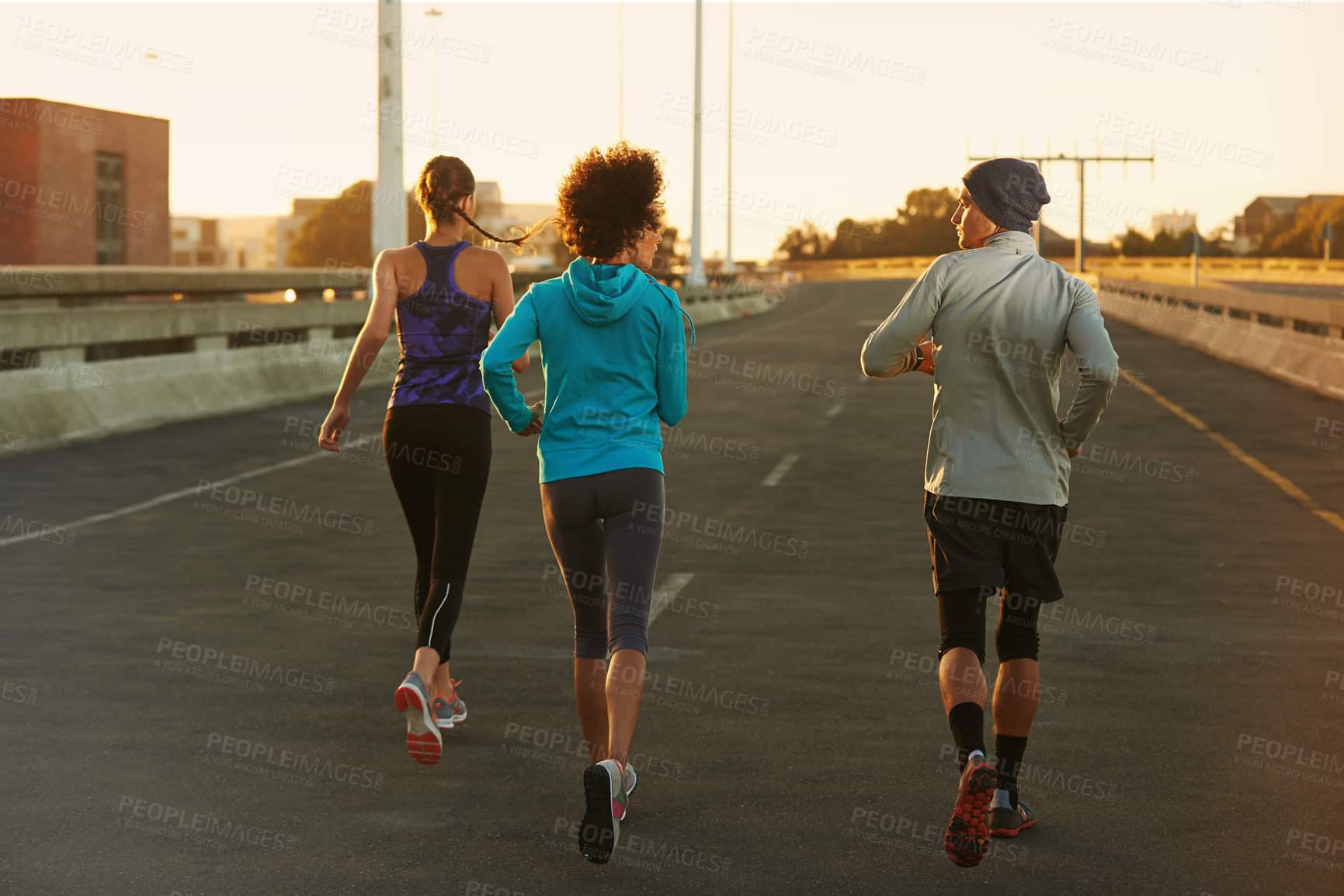 Buy stock photo Fitness, street and people running at sunset together for training, commitment and health in city. Evening, exercise and group of friends on road for urban workout with outdoor challenge from back