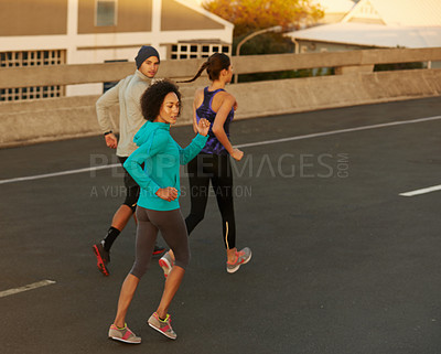 Buy stock photo Exercise, city and people running at sunset together for sports training, commitment and body health. Evening, workout and group of friends on road for urban fitness with outdoor challenge on street