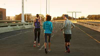 Buy stock photo Fitness, road and people running at sunset together for training, commitment and health in city. Evening, exercise and group of friends on street for urban workout with outdoor challenge from back