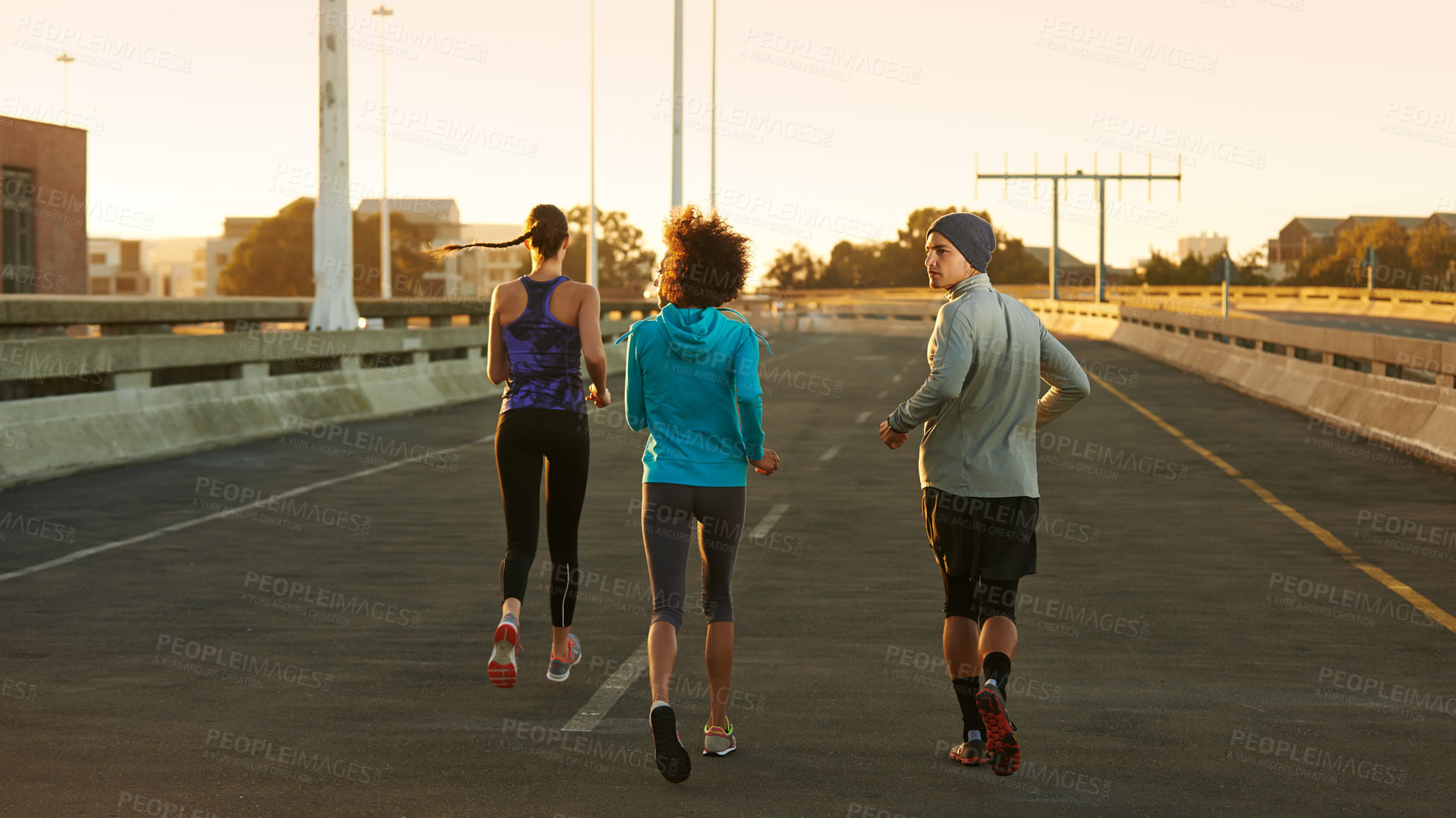 Buy stock photo Fitness, road and people running at sunset together for training, commitment and health in city. Evening, exercise and group of friends on street for urban workout with outdoor challenge from back