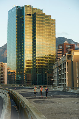 Buy stock photo City, building and people running at sunset together for fitness, training or commitment to healthy body. Evening, exercise and group of friends on street for urban workout with outdoor challenge