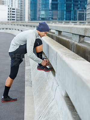 Buy stock photo Runner, man or tie shoelace in city for morning jog, fitness or getting ready for cardio workout in street. Athlete, person or prepare running shoes on urban bridge for exercise, training or marathon