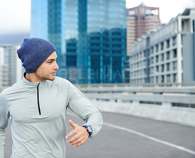 Buy stock photo Cropped shot of a young man jogging through empty city streets
