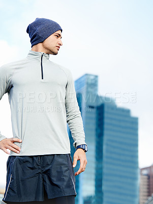 Buy stock photo Shot of a young jogger taking in his urban surroundings 