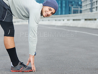 Buy stock photo Portrait of a young male jogger stretchng in the street before a run