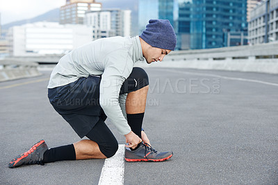 Buy stock photo Runner, man or tie sneakers in city for morning jog, fitness or getting ready for cardio workout in street. Athlete, person or prepare running shoes on urban bridge for exercise, training or marathon