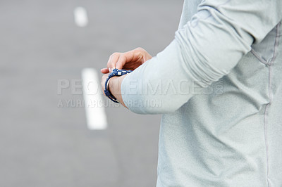 Buy stock photo Cropped shot of a jogger checking the time while out for a run in the city