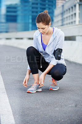 Buy stock photo Woman, fitness and tying shoes in city for running, sports or training on street or road. Health, jogging and runner or female athlete getting ready for exercise, marathon or cardio with music