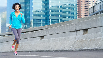 Buy stock photo Shot of a young woman jogging through the city