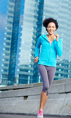 Buy stock photo Shot of a young woman jogging through the city