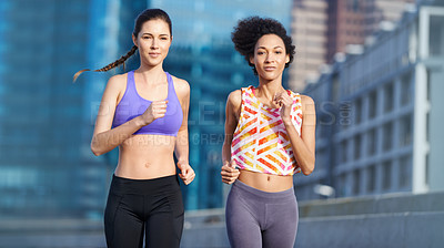 Buy stock photo Portrait of two friends jogging together through the city streets
