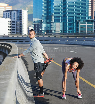 Buy stock photo Portrait of two friends stretching together before a run through the city streets