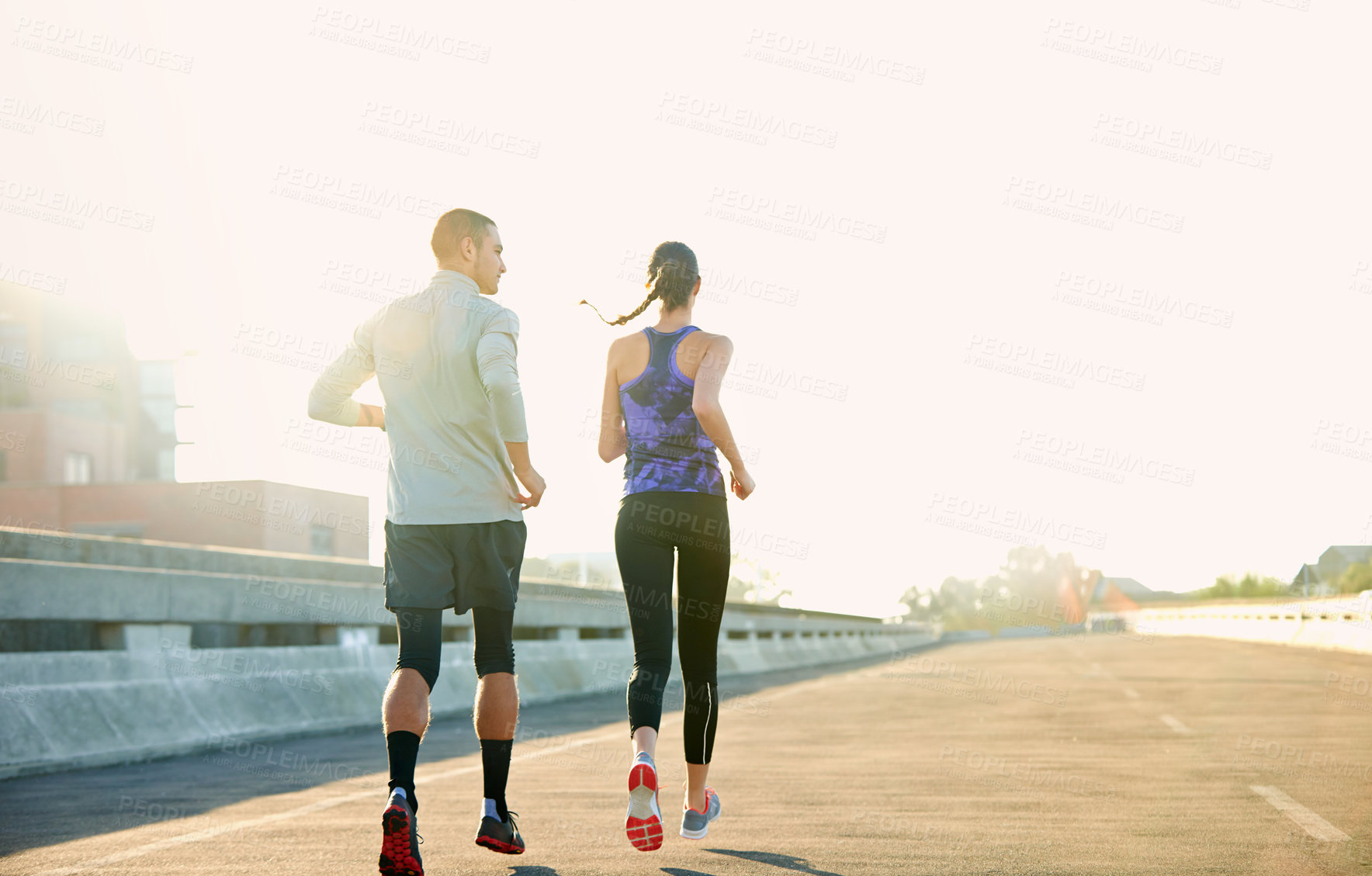 Buy stock photo Rearview shot of two friends jogging through the city