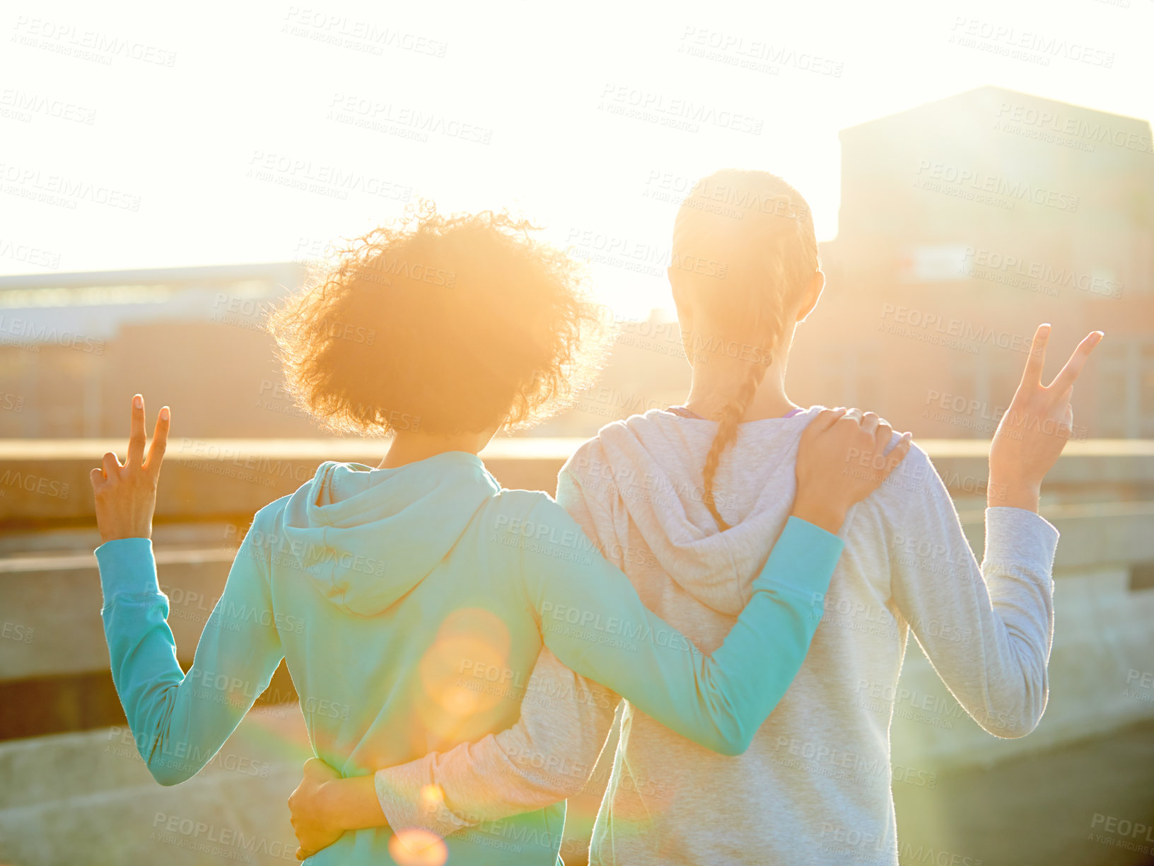 Buy stock photo Rearview shot of two female joggers doing peace signs while taking in the sunrise