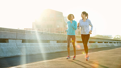 Buy stock photo Shot of two friends jogging together in the city