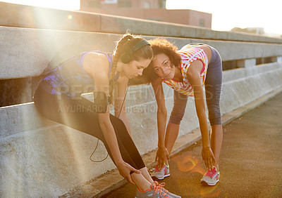 Buy stock photo Shot of two female joggers preparing for a jog in the city