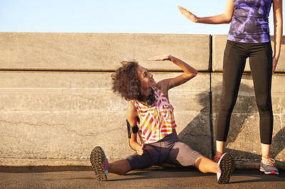 Buy stock photo Shot of a female jogger sitting on the road and high-fiving her standing partner