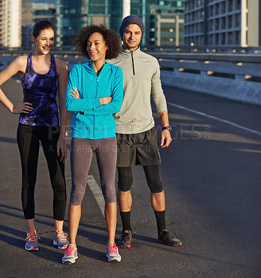 Buy stock photo Shot of three young joggers standing in an empty road in the city