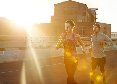 Buy stock photo Shot of two friends out jogging in the city in the early morning