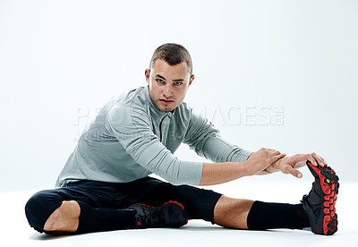 Buy stock photo Portrait of a young man stretching his legs against a white background