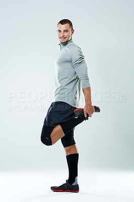 Buy stock photo Full length shot of a young man doing stretches over a gray background