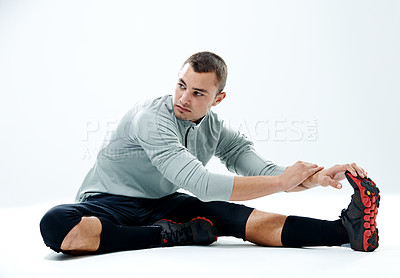 Buy stock photo Shot of a young man sitting in a studio while doing stretches