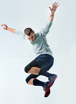 Buy stock photo Shot of a young man jumping in mid air against a gray background